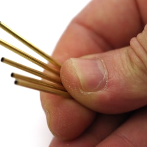 May include: A bundle of five gold-colored brass tubes.