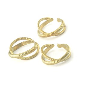 Op de afbeelding: Drie gouden, open ringen met een getextureerd oppervlak. De ringen zijn ontworpen om aan de vinger te worden gedragen, met de uiteinden die elkaar overlappen.