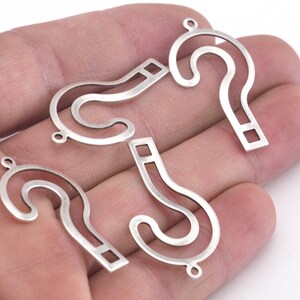 May include: Four silver question mark charms with a loop at the top for attaching to jewellery or other crafts.