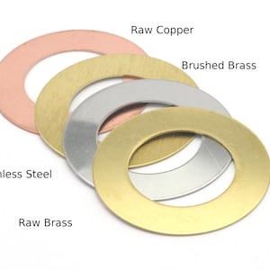 Pode incluir: Quatro anéis de metal em diferentes acabamentos: cobre bruto, latão escovado, aço inoxidável e latão bruto. Os anéis estão empilhados uns sobre os outros, com o anel de latão bruto na parte inferior.