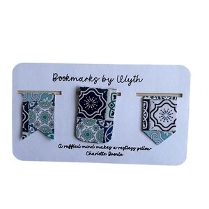 May include: Three fabric bookmarks with a decorative pattern in shades of blue, teal, and white are displayed on a white card. The card reads "Bookmarks by Ulyth" and includes a quote by Charlotte Bronte.