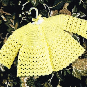 May include: A yellow crocheted baby cardigan with a button closure and a scalloped edge.