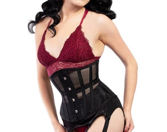 Peut inclure: Un corset noir avec un panneau transparent et des jarretelles est associé à un bralette en dentelle bordeaux. Le modèle porte des bas couleur chair. L'ensemble est une lingerie d'inspiration vintage.