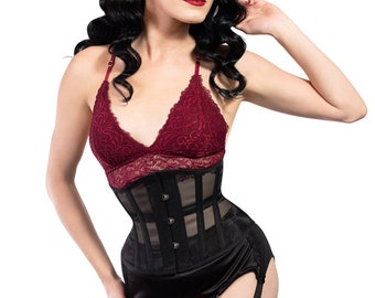 Peut inclure: Un corset noir avec un design à panneaux transparents, associé à un bralette en dentelle bordeaux et une ceinture porte-jarretelles. La ceinture porte-jarretelles a quatre bretelles avec des fermoirs en métal. Bas de couleur chair.