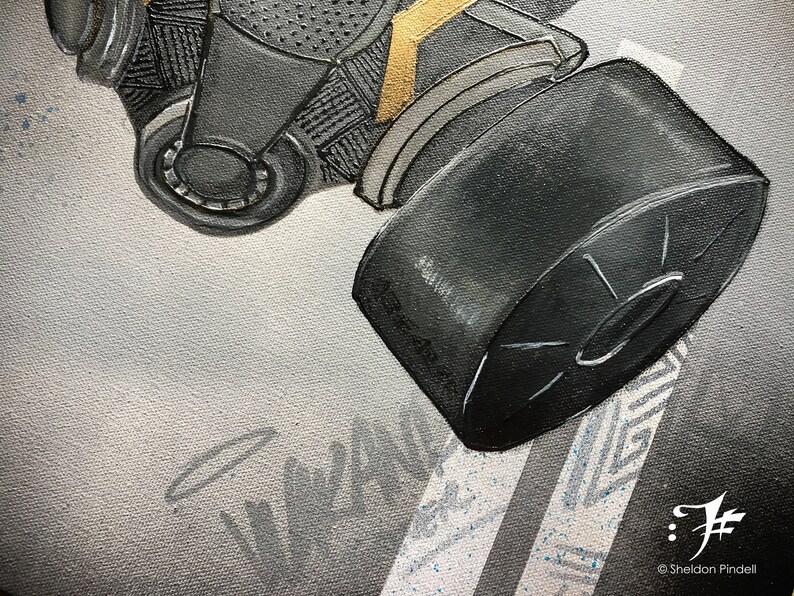 Puede incluir: Primer plano de una m&aacute;scara de gas negra con un acento dorado. La m&aacute;scara tiene un filtro redondo unido al lado. El fondo es un lienzo gris claro con un patr&oacute;n blanco y gris.