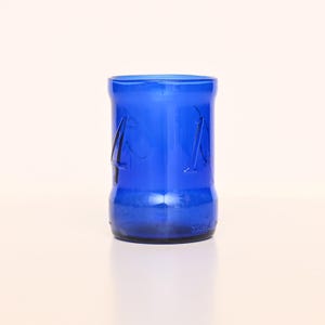 May include: A vibrant blue glass tumbler with the number "41" etched on the side. The cylindrical glass has a thick base and a slightly flared rim. The glass is a deep, saturated blue color.