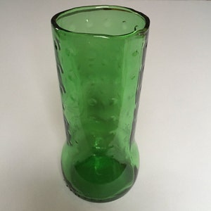 May include: A green glass vase with a textured surface. The vase has a wide mouth and a rounded bottom.