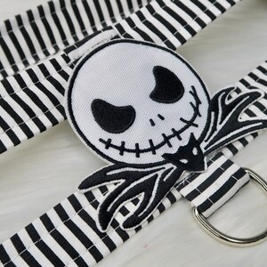 May include: Black and white striped fabric with a black and white embroidered Jack Skellington patch. The fabric has a silver metal ring attached.