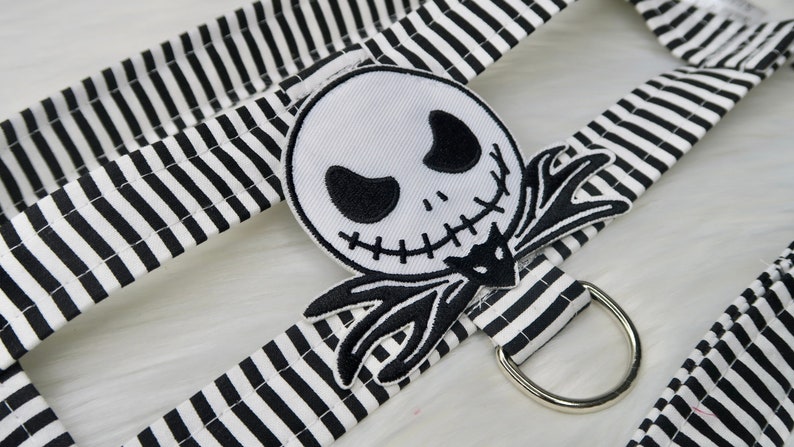 May include: Black and white striped fabric with a black and white embroidered Jack Skellington patch. The fabric has a silver metal ring attached.
