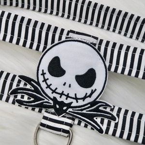 May include: Black and white striped fabric with a black and white embroidered Jack Skellington patch. The patch is a close-up of Jack Skellington's face with a stitched smile and black eyes.
