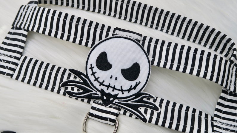 May include: Black and white striped fabric with a black and white embroidered Jack Skellington patch. The patch is a close-up of Jack Skellington's face with a stitched smile and black eyes.
