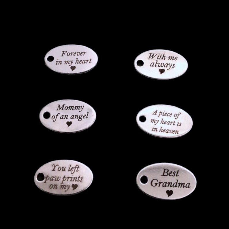 May include: Six silver oval pendants with various engraved messages and heart symbols. The messages include "Forever in my heart," "With me always," "Mommy of an angel," "A piece of my heart is in heaven," "You left paw prints on my," and "Best Grandma."