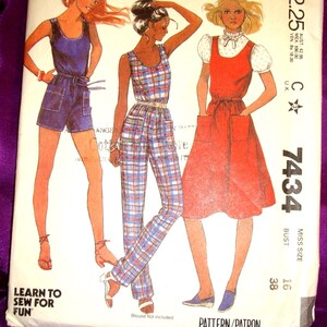 May include: A McCall's sewing pattern envelope 7434 featuring illustrations of three outfits: a blue romper with pockets, a plaid jumpsuit with a belt, and a red sleeveless dress with a white puff-sleeve blouse underneath. The text includes McCall's, 7434, and Learn to Sew for Fun.