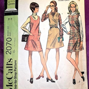 Peut inclure: Patron de couture vintage McCall's 2070. Le patron présente des illustrations de trois femmes portant des robes-salopettes avec différents cols. Le patron comprend le texte "Quickie" et "New Easy". Le patron est pour les tailles 16 et 38.