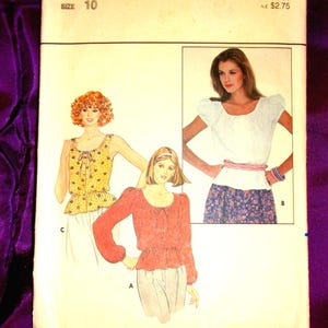 May include: Vintage Butterick sewing pattern, size 10, featuring illustrations of three different blouses. The pattern cover has the text "BUTTERICK 4350" and price information. The background is a deep purple fabric.