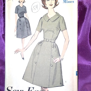 May include: A vintage sewing pattern envelope for a dress, labeled 3020 size 14 Misses. The illustration shows a short-sleeved, collared dress with a belted waist and double-breasted button detailing on the skirt. The text reads Sew-Easy Advance.