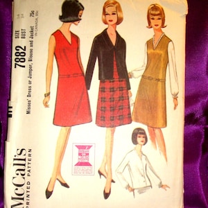 May include: A McCall's 7882 printed sewing pattern envelope for a dress, jumper, blouse, and jacket. The front features illustrations of four outfits: a red sleeveless dress, a black jacket over a plaid skirt, a tan jumper with a white blouse, and a white blouse.