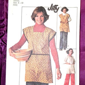 May include: Simplicity sewing pattern 7708, featuring a woman wearing an apron. The pattern includes a Jiffy design and is for small sizes 8-10. The apron is yellow with a small floral pattern and black trim.