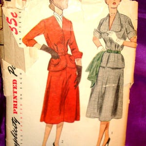 May include: A vintage Simplicity sewing pattern envelope featuring illustrations of two outfits. One is a solid red jacket and skirt set with dark gloves, and the other is a grey and white checkered jacket and skirt set with a green belt and white gloves.