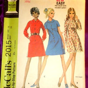 May include: Vintage McCall's 2015 sewing pattern for Misses' dresses. The pattern features three dress styles, including a mini-length option. The cover art showcases illustrations of the dresses in red, blue, and floral prints. The pattern includes a two-color guide.