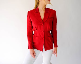 Op de afbeelding: Een rode blazer met een fluwelen kraag en een enkele knoopsluiting. De blazer heeft een aansluitende pasvorm en is gemaakt van een gladde stof.