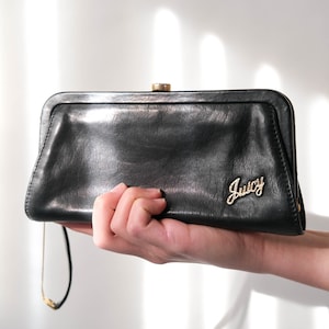 May include: A black leather clutch purse with a gold clasp and the word "Juicy" in gold lettering.
