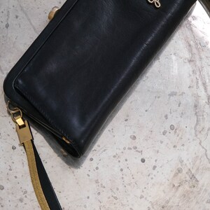 May include: A black leather wallet with a gold chain strap and the word "Lucy" embossed in gold on the front.