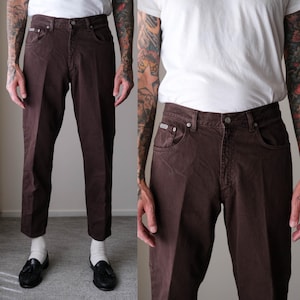 May include: Brown denim pants with a classic five-pocket design. The pants have a straight leg cut and a button and zipper closure. The pants are a solid brown color and appear to be made of a durable denim material.