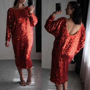 May include: A red sequined dress with long sleeves and a midi length. The dress has a boat neckline in the front and a low scoop back. The dress is covered in small, shiny sequins.