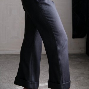 May include: Dark gray wide-leg trousers with a cuffed hem. The pants are paired with black high-heeled sandals with delicate straps and rhinestone accents. The fabric appears to be a smooth, woven material.