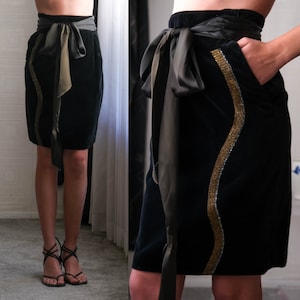 May include: A black velvet skirt with a gold beaded trim and a black satin sash tied in a bow at the waist.