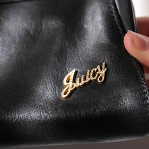 May include: Black leather wallet with a gold Juicy Couture logo.