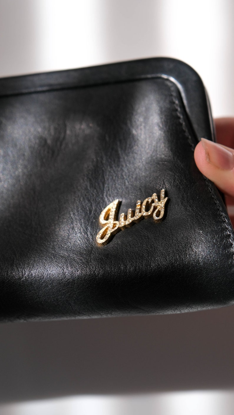 May include: Black leather wallet with a gold Juicy Couture logo.
