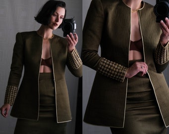 May include: A brown blazer with gold trim and a matching skirt. The blazer has a deep V-neckline and the skirt is knee-length.