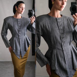 May include: A grey long-sleeved top with a peplum design and button-up front. The top is paired with a mustard-coloured pencil skirt. The outfit is captured in a mirror reflection.