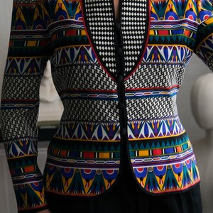 May include: A black and white patterned blazer with a colorful geometric design. The blazer has a mandarin collar and a button closure.