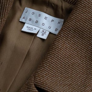 May include: Close-up of a brown blazer with a subtle white pinstripe pattern. The interior lining is a solid tan color. The label reads "JOSEPH ABBOUD" and "MADE IN ITALY". The size is 42/8.