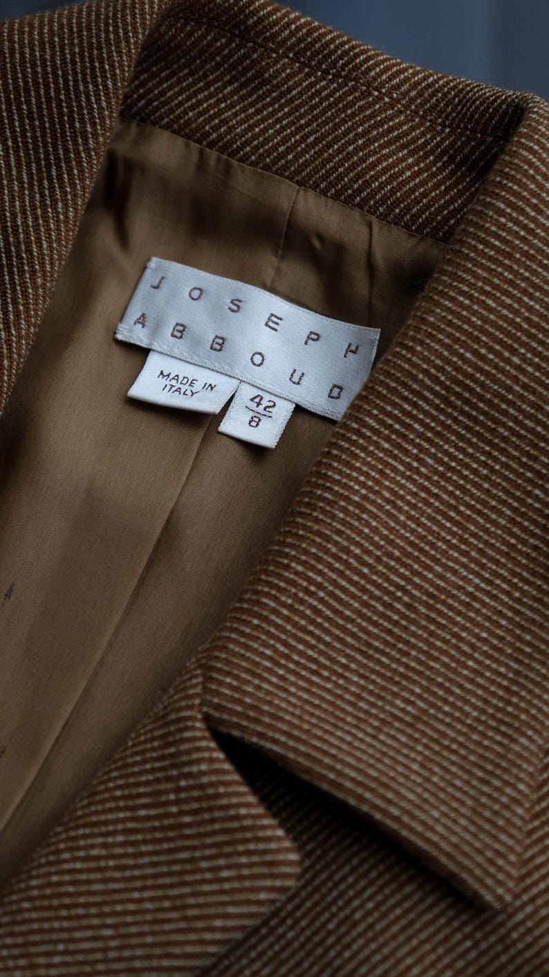 May include: Close-up of a brown blazer with a subtle white pinstripe pattern. The interior lining is a solid tan color. The label reads "JOSEPH ABBOUD" and "MADE IN ITALY". The size is 42/8.