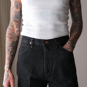 Peut inclure: D&eacute;bardeur blanc c&ocirc;tel&eacute; et jean en denim noir. Le jean a une conception classique &agrave; cinq poches avec une fermeture boutonn&eacute;e et zipp&eacute;e. Le mod&egrave;le a des tatouages sur les deux bras.