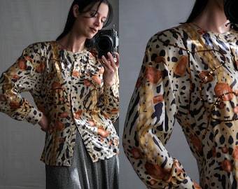 May include: A brown and beige leopard print button-up shirt with gold accents. The shirt has a long sleeve and a relaxed fit.