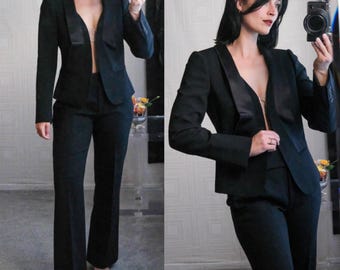 May include: A black blazer with a satin lapel and matching pants. The blazer has a notched collar and long sleeves. The pants have a wide leg.