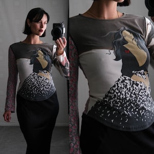 Puede incluir: Una camisa de manga larga con un estampado gráfico de una mujer con un vestido negro y una falda de estampado de leopardo blanco y negro. La camisa está hecha de una tela suave y elástica y tiene un ajuste holgado.