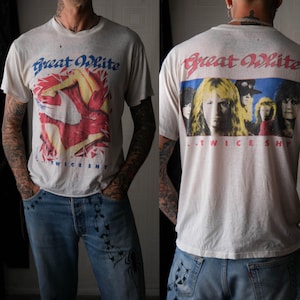 May include: Cream-colored vintage t-shirt featuring the band name "Great White" in blue and red. The front graphic shows a woman in red and white. The back of the shirt has a band photo and the text ".TWICE SHY."