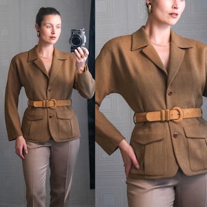 May include: A brown blazer with a matching belt and tan pants. The blazer has a tailored fit with a notched collar, two front pockets, and a button closure. The belt is a light brown color with a large buckle. The pants are a neutral tan color.