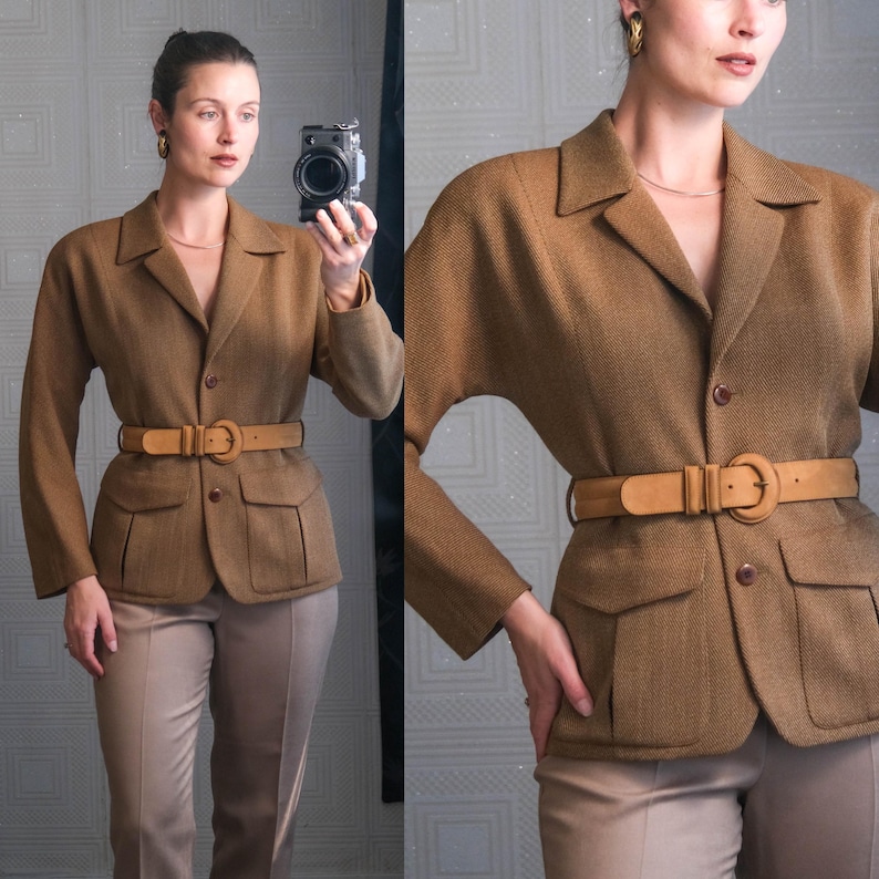 May include: A brown blazer with a matching belt and tan pants. The blazer has a tailored fit with a notched collar, two front pockets, and a button closure. The belt is a light brown color with a large buckle. The pants are a neutral tan color.