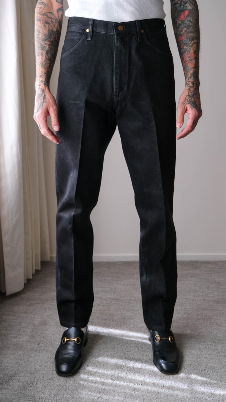 Peut inclure: Pantalon en denim noir de coupe classique. Le pantalon a une fermeture boutonn&eacute;e et une jambe droite. Le mod&egrave;le porte des mocassins en cuir noir avec des accessoires dor&eacute;s. Le pantalon est d&eacute;lav&eacute; fonc&eacute;.