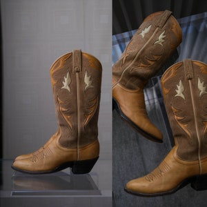Op de afbeelding: Twee paar bruine suède cowboylaarzen met ingewikkelde stiksels en een puntige neus.