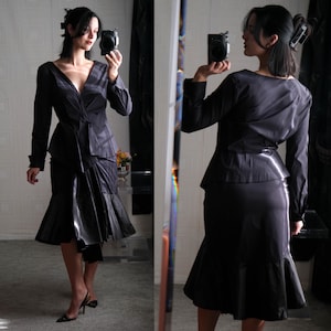 May include: A black long-sleeved dress with a ruffled skirt and a V-neckline. The dress is fitted at the waist and has a flowing skirt.