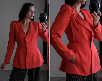 Op de afbeelding: Een felrode blazer met een getailleerde pasvorm en een licht uitlopende zoom. De blazer heeft een enkele knoopsluiting en een puntige kraag.