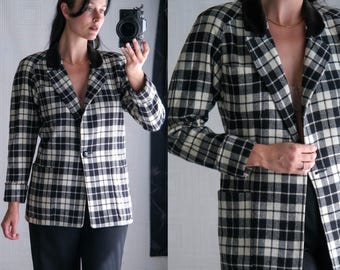 May include: A black and cream plaid blazer with a black velvet collar and two front pockets. The blazer has a single-button closure and is worn with black pants. The jacket's pattern is a classic, timeless design.